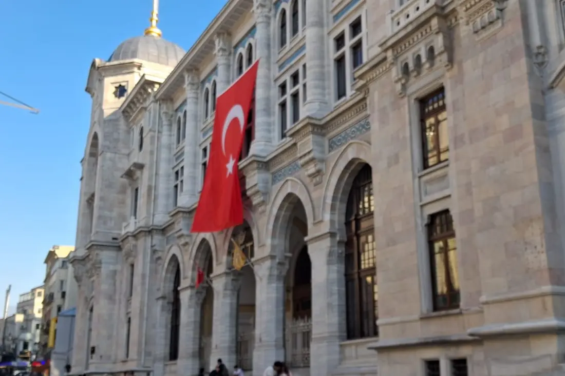 The stone front of the Sirkeci Central Post Office with arched windows and a Turkish flag.
